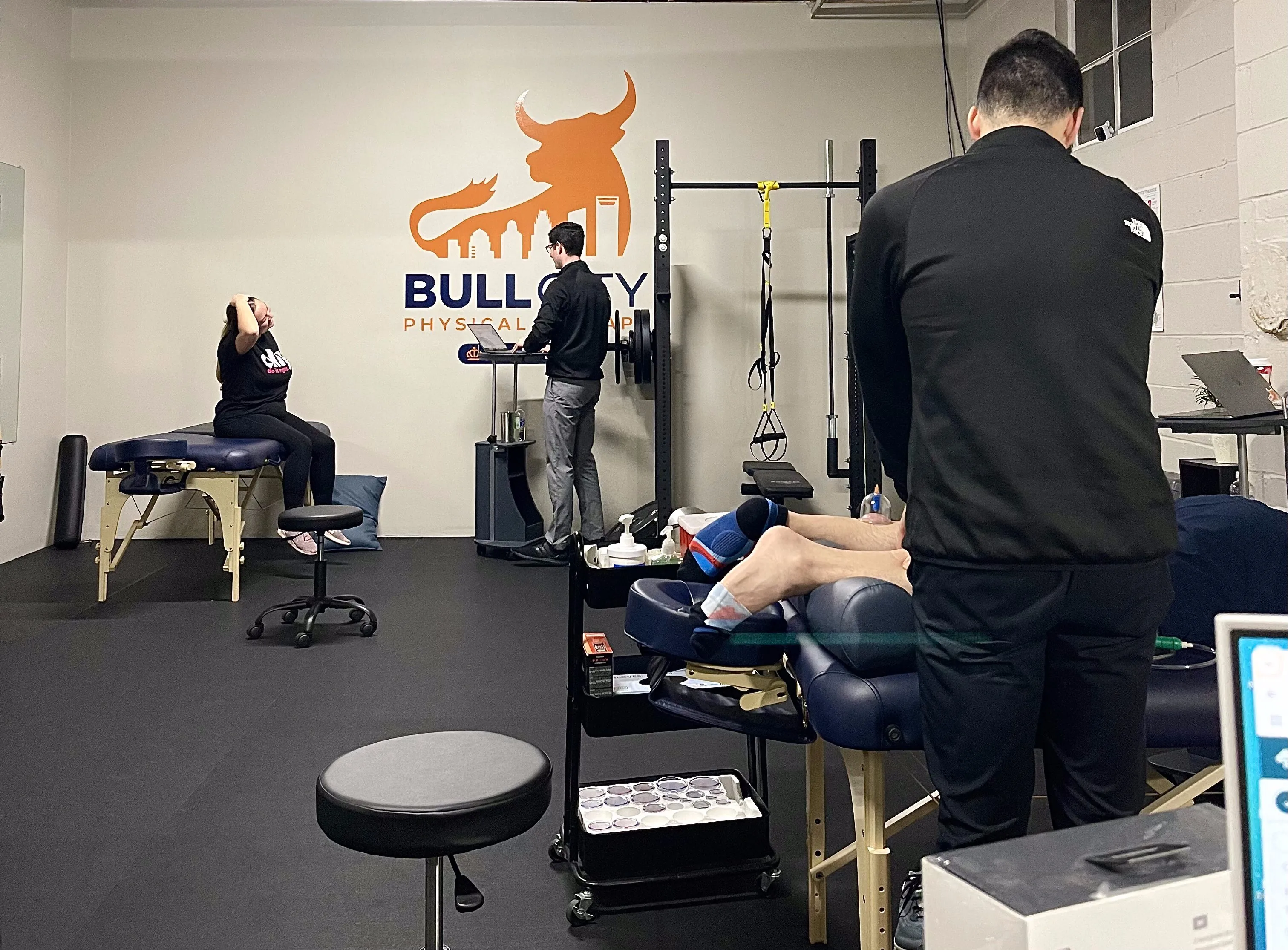 Physical therapy session in progress at Bull City Physical Therapy clinic, showing therapists assisting patients with exercises and treatments.